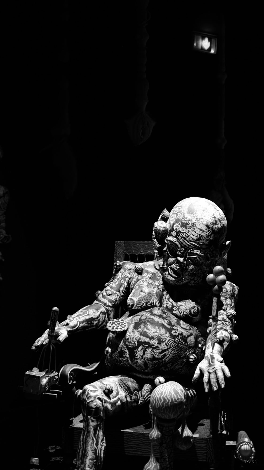 Une sculpture ornée d'une figure assise qui émerge de l'obscurité.