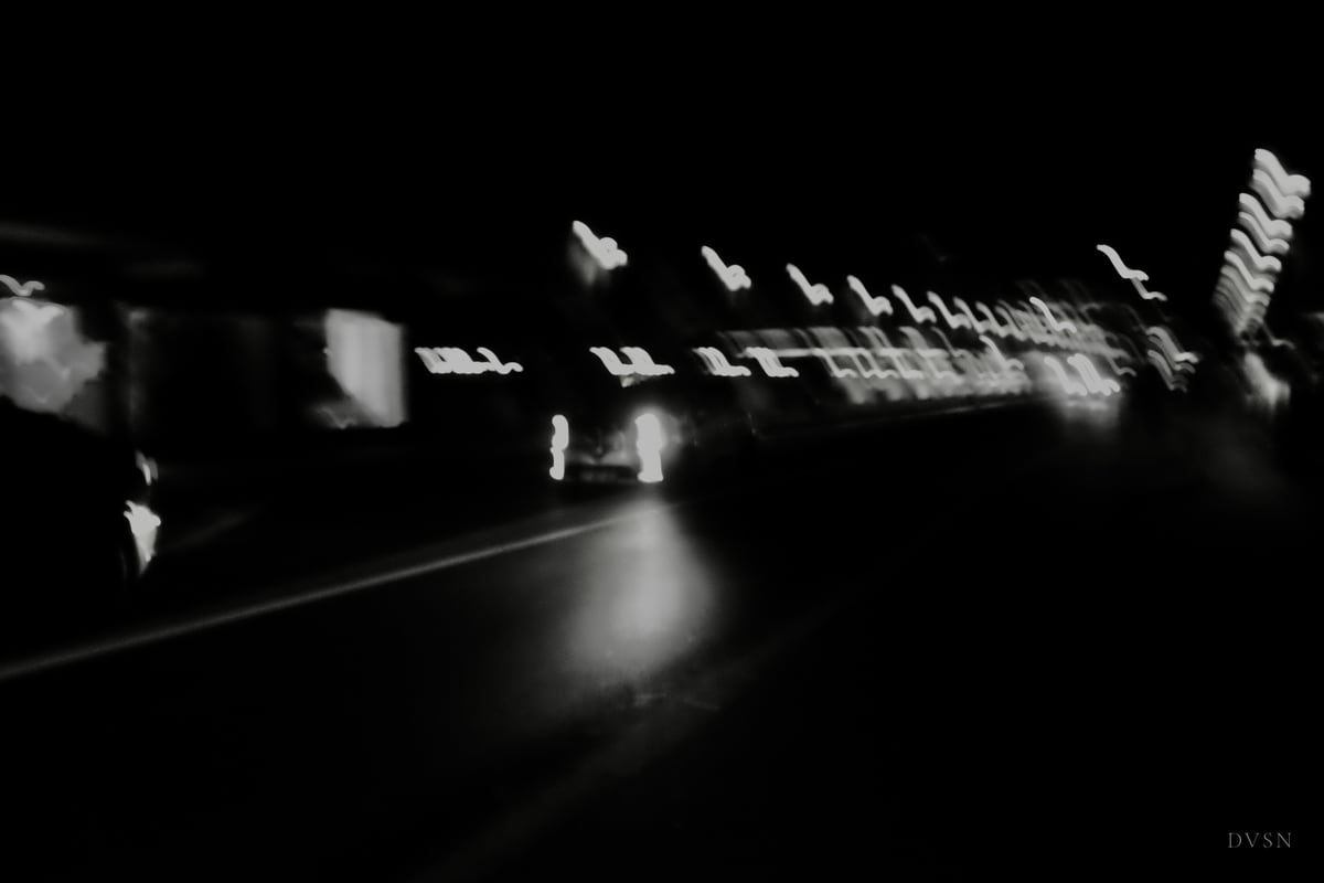 Des traînées de lumières urbaines, floues de mouvement, dans la nuit.